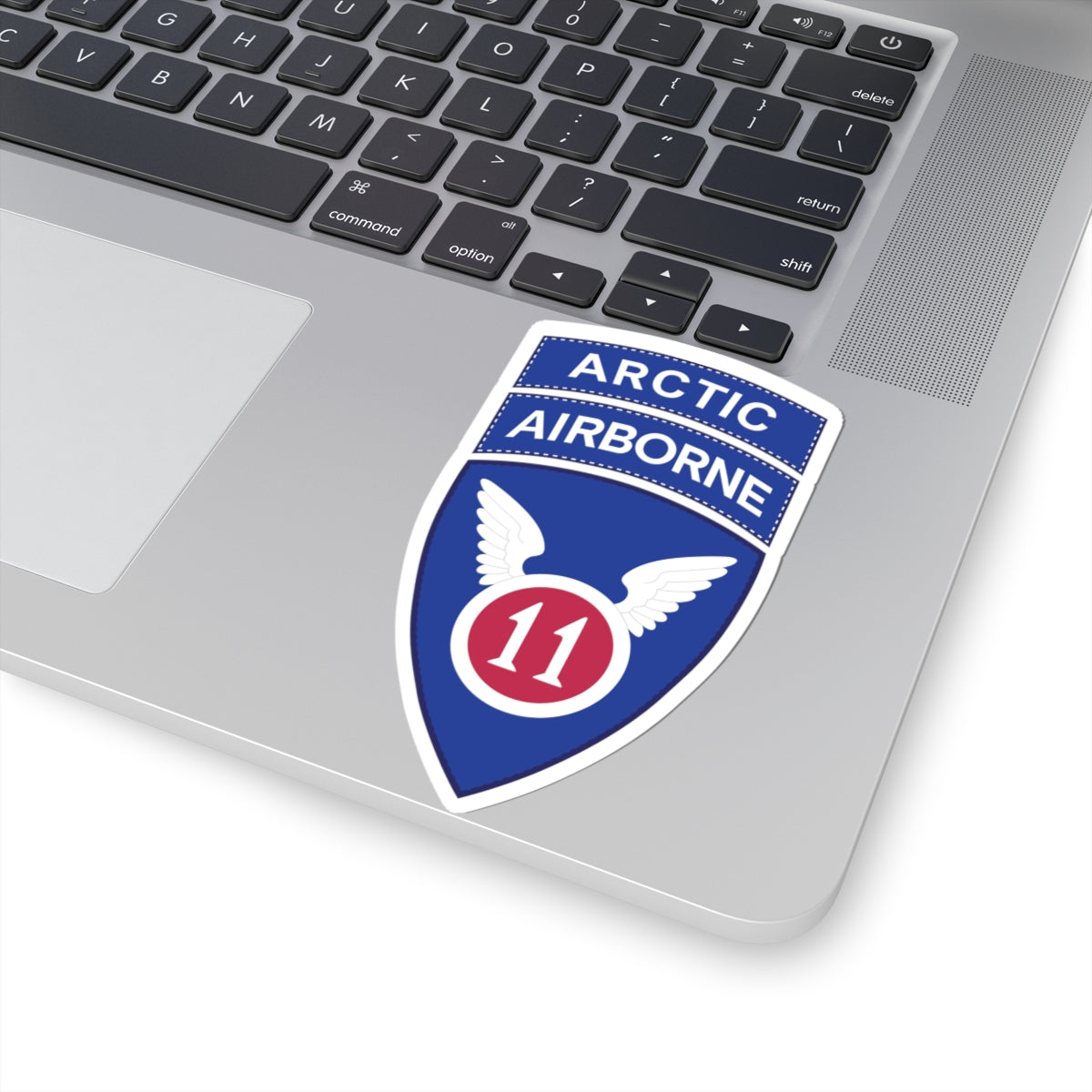 A kiss-Cut Stickers depicting the 11th Airborne Division, reactivated in 2022, is a U.S. Army unit specializing in cold-weather and Arctic operations. Nicknamed the "Arctic Angels," its shoulder sleeve insignia (SSI) features a red angel wing and sword on a blue background, and it is often worn with the "Arctic" tab to denote its mission focus.