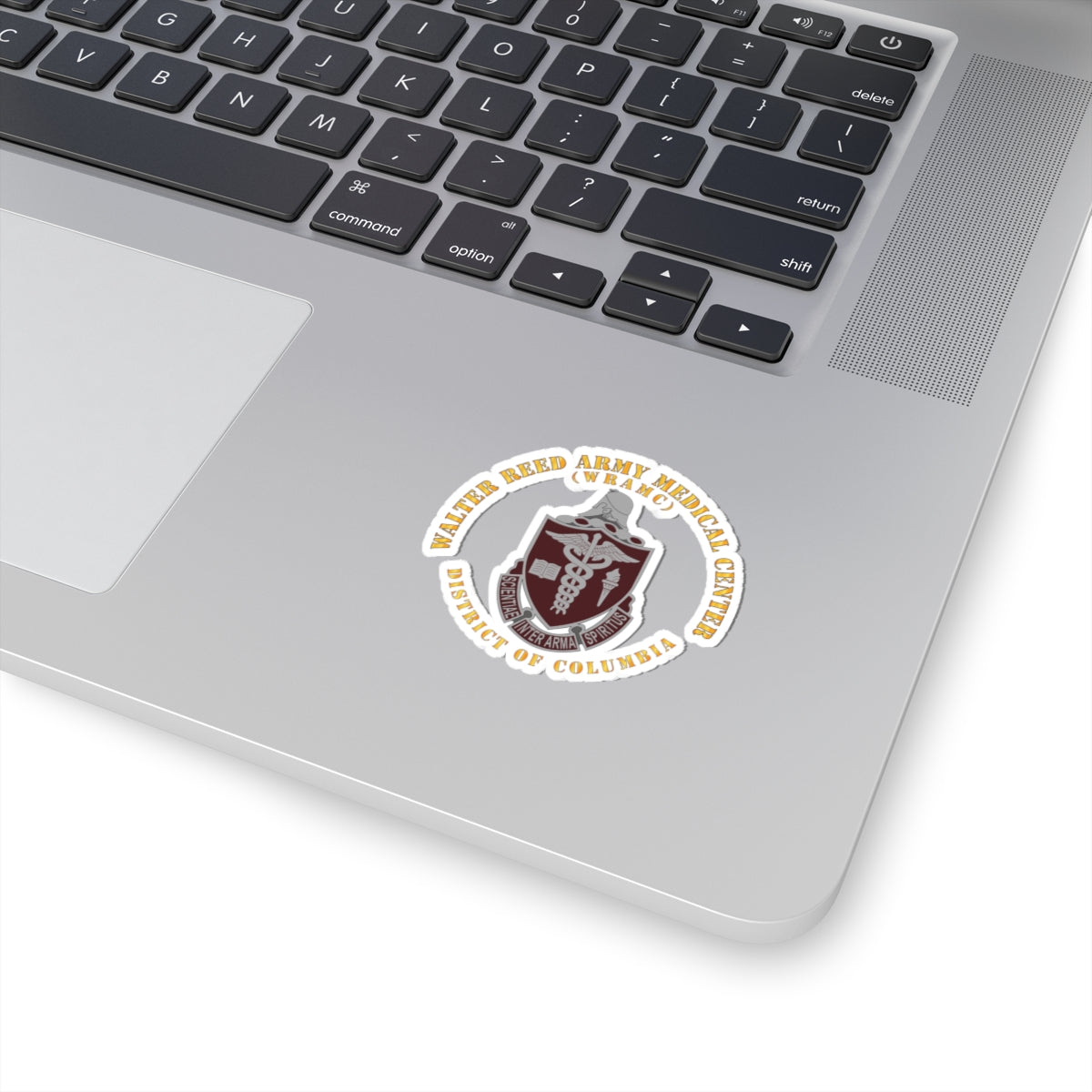 A sticker with the Walter Reed Army Medical Center, District of Columbia, crest featuring a building and medical symbols in grey and colorless design on a white background.