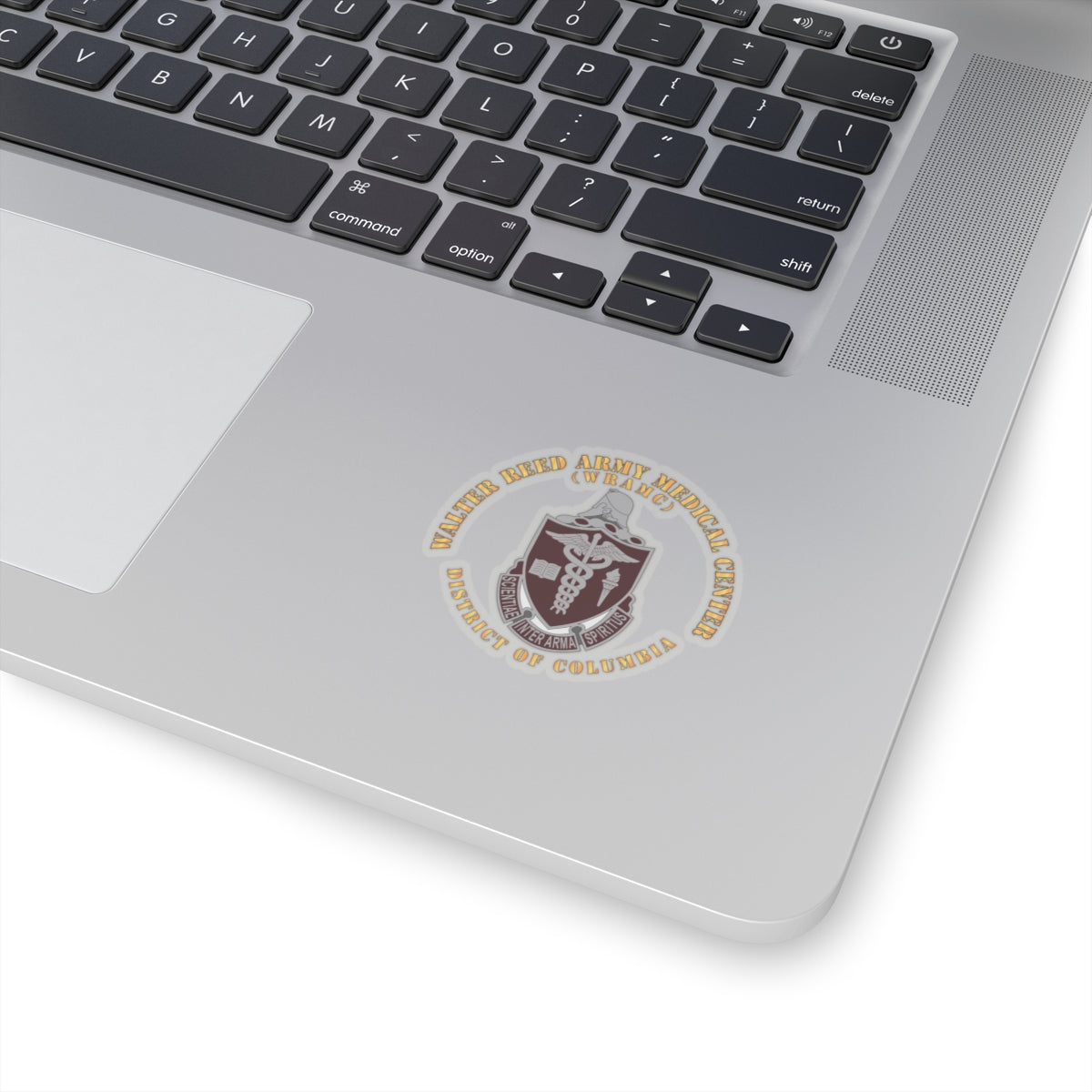 A sticker with the Walter Reed Army Medical Center, District of Columbia, crest featuring a building and medical symbols in grey and colorless design on a white background.