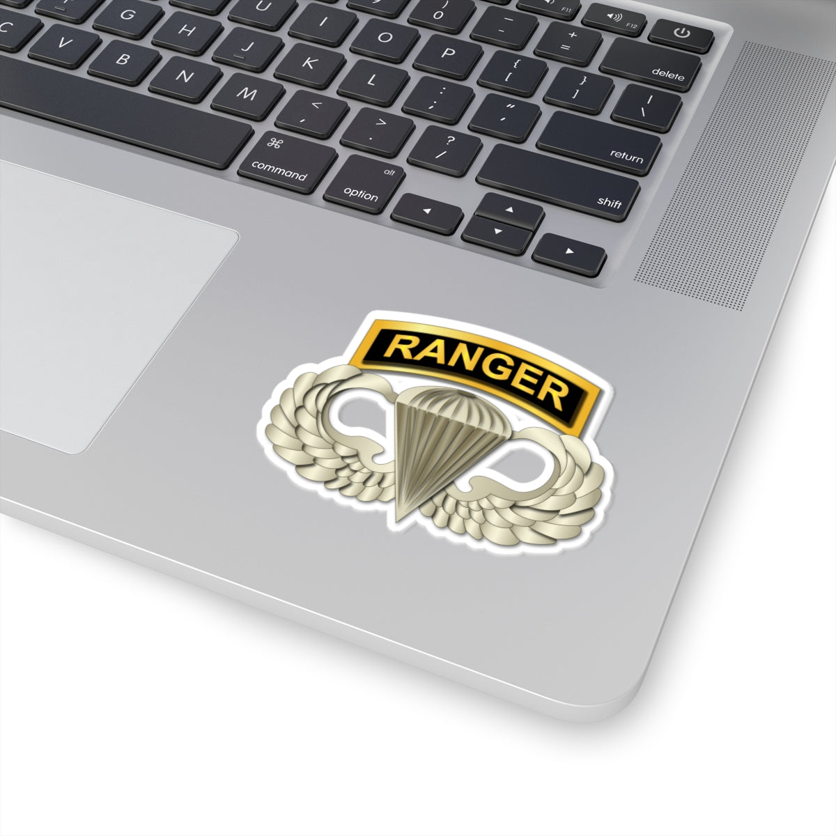 A sticker with a gold-colored ribbon labeled 'RANGER' above a wings and parachute design, signifying the Airborne Badge.