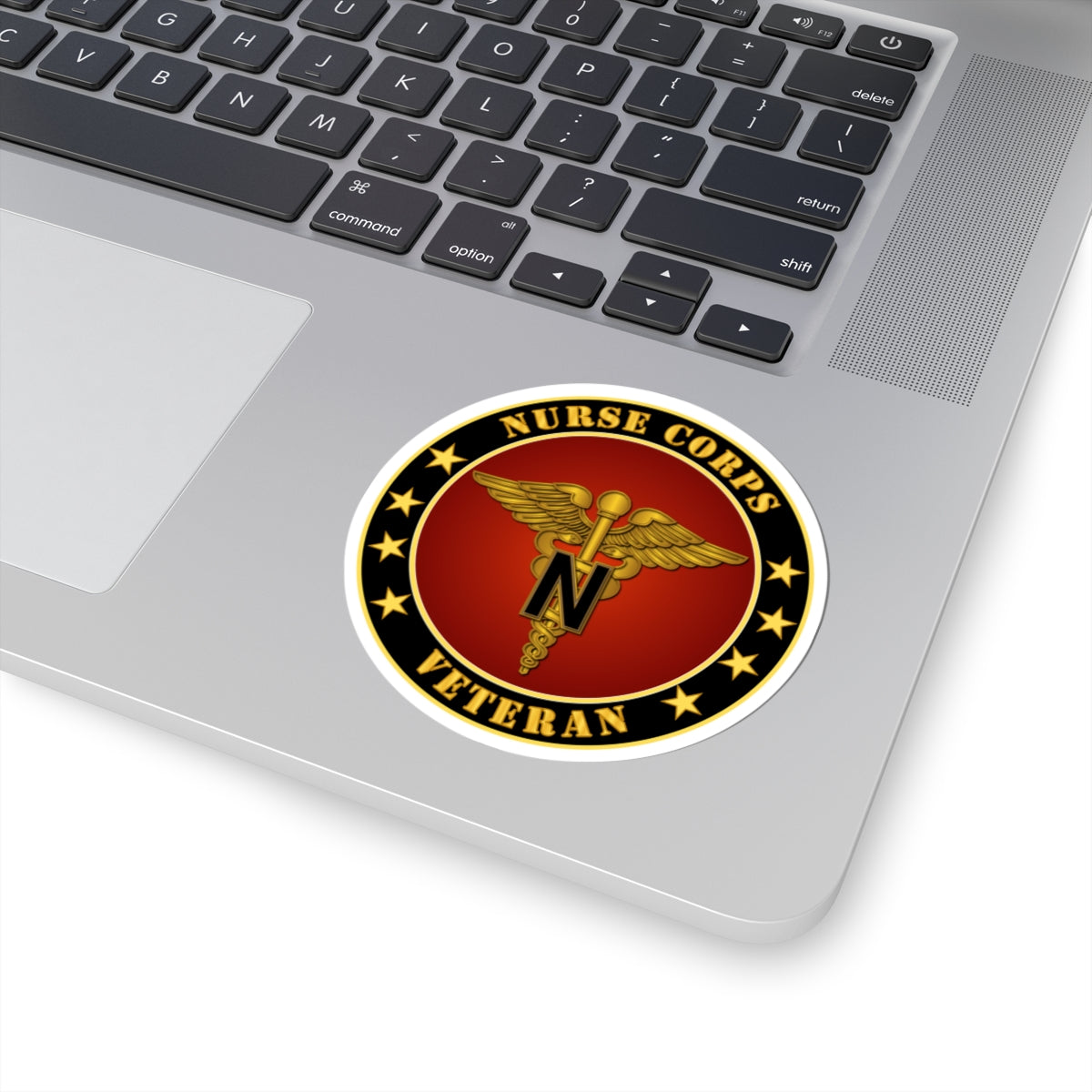 A circular sticker with a red background featuring the caduceus symbol, stars, and the text 'NURSE CORPS VETERAN'. The sticker has a golden border.