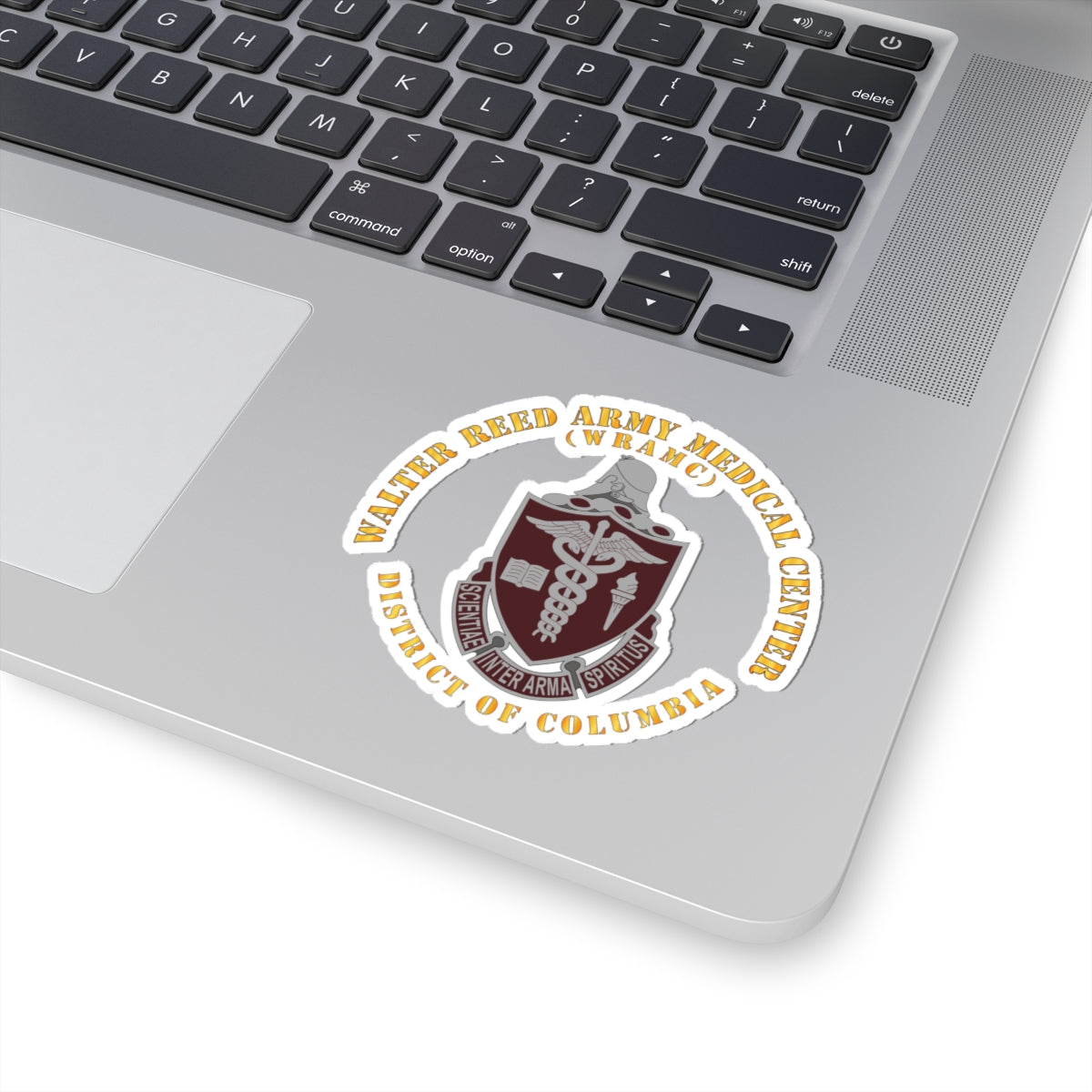 A sticker with the Walter Reed Army Medical Center, District of Columbia, crest featuring a building and medical symbols in grey and colorless design on a white background.