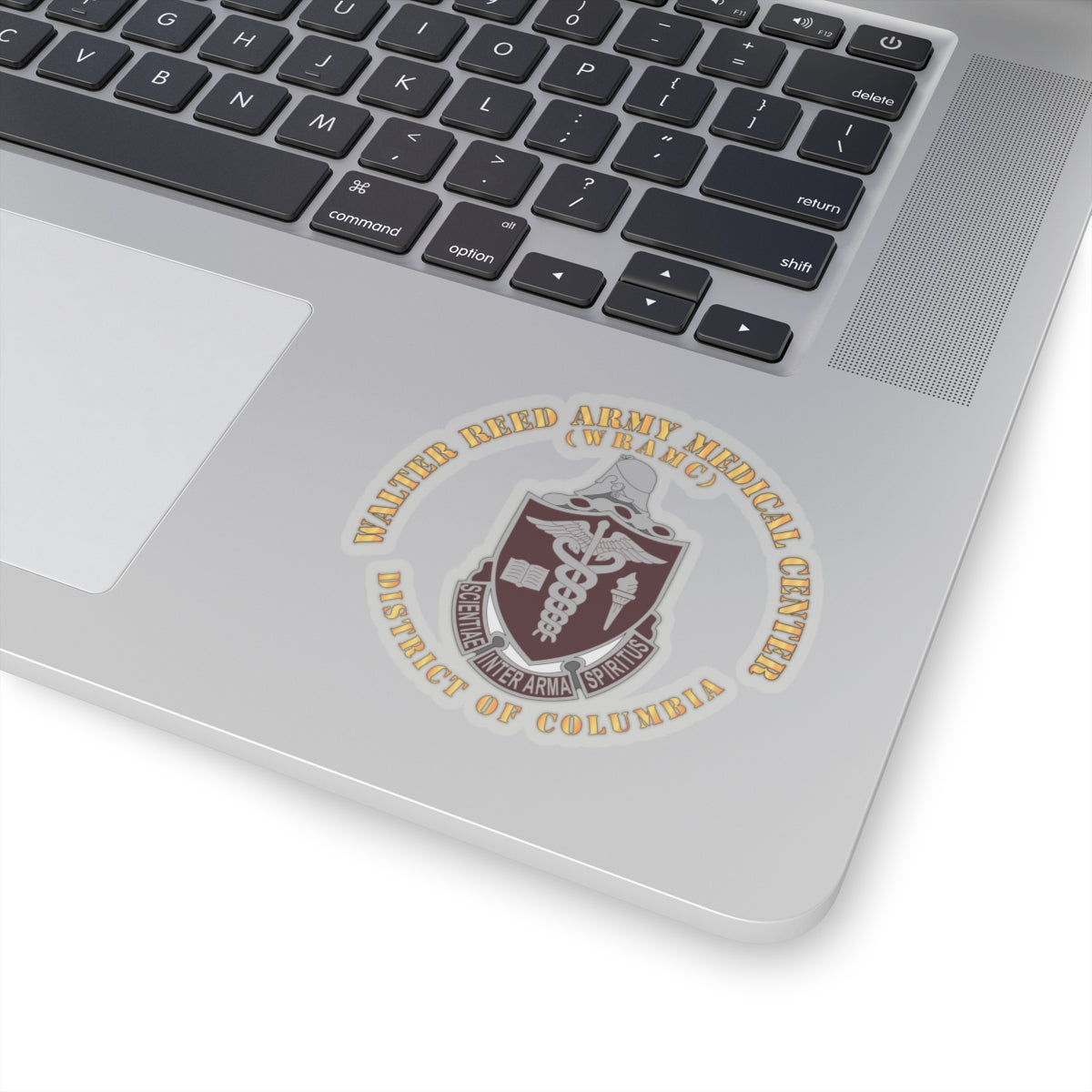 A sticker with the Walter Reed Army Medical Center, District of Columbia, crest featuring a building and medical symbols in grey and colorless design on a white background.